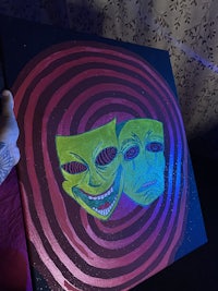 a person is holding a painting with two faces on it